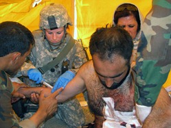 Senior Airman Robin Mock helps stabilize an Afghan national police officer with a gunshot wound in the Laghman Province in Afghanistan. Laghman Provincial Reconstruction Team medics and an Afghan national army doctor were conducting a joint-medical outreach in Sur Ghar Village at the time of the incident. The Afghan officer was wounded during an unrelated poppy eradication mission a few kilometers away. U.S. Air Force photo - RELEASED.